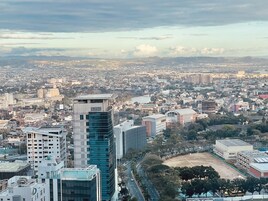 Un paisaje urbano con edificios modernos, incluyendo un rascacielos destacado con fachada de vidrio.
