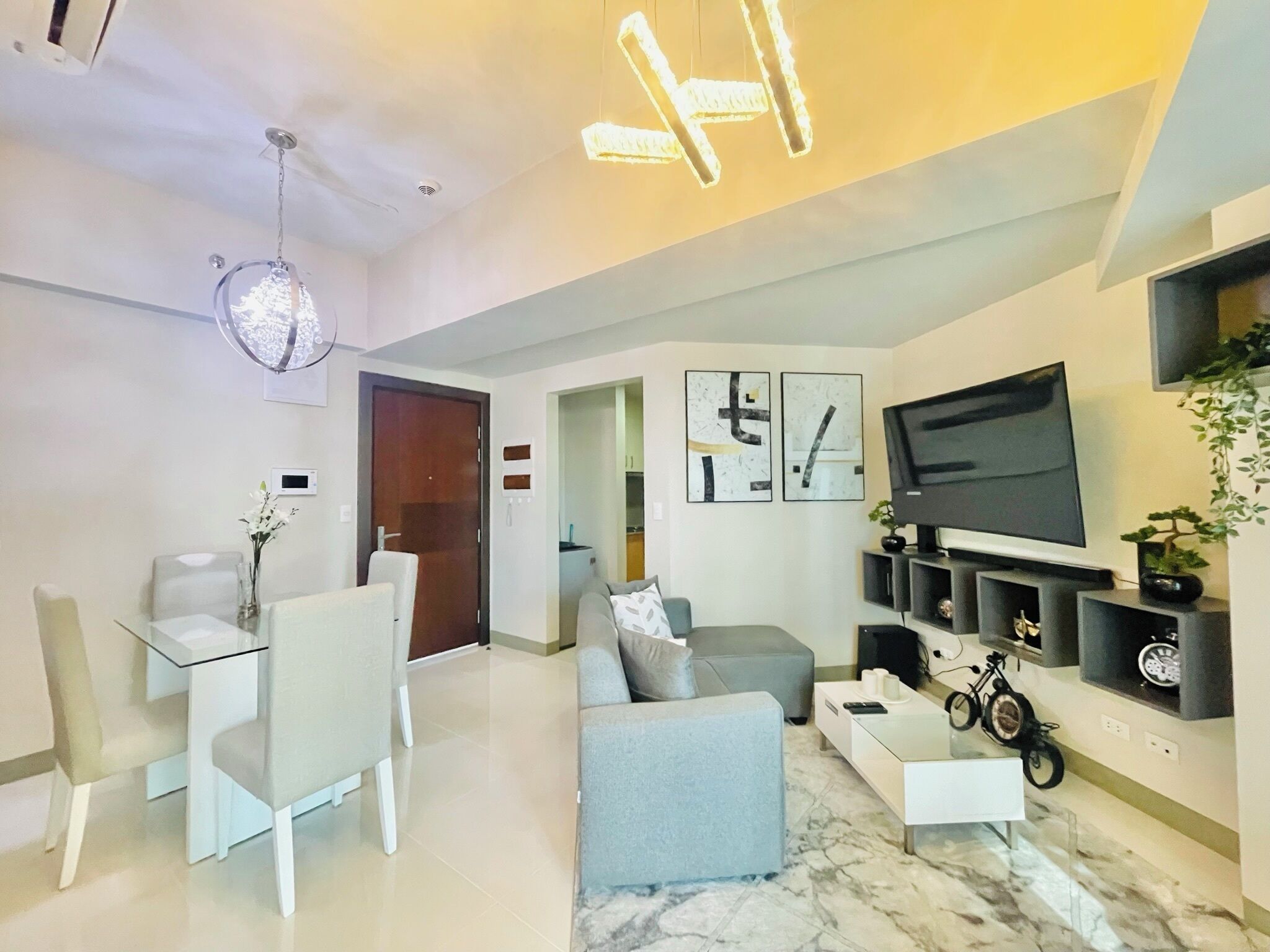 A modern living room with a sofa, dining table, chairs, a TV, and a bike.