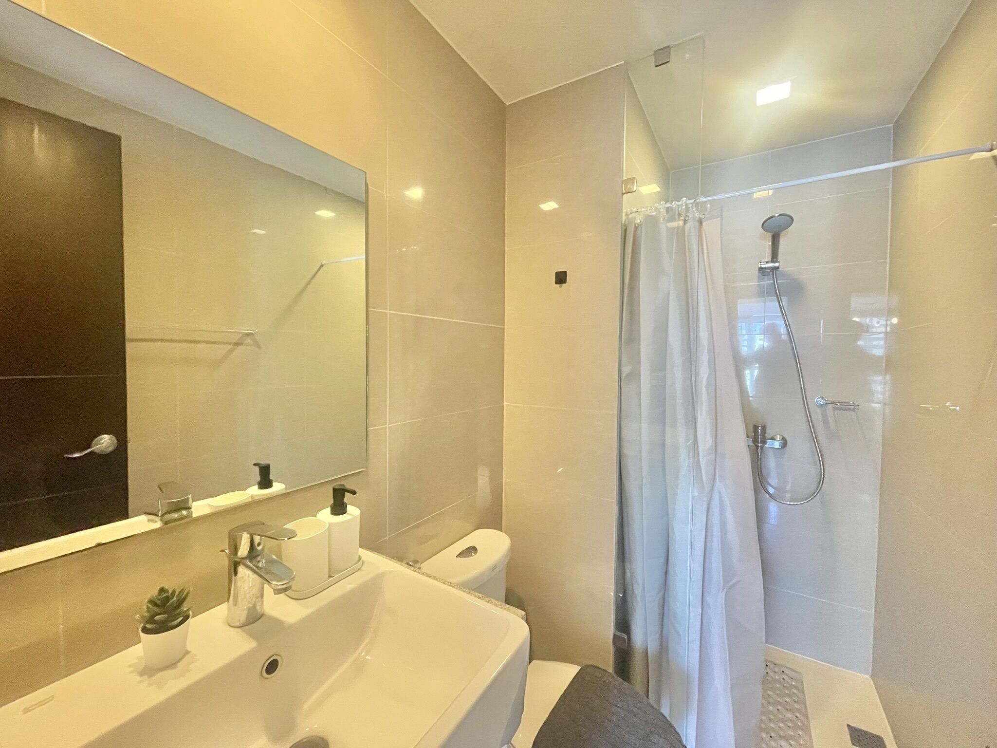 A modern bathroom with a sink, mirror, toilet, and shower.