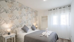 A bedroom with a bed, nightstands, a bedside lamp, a towel, and a window with curtains.