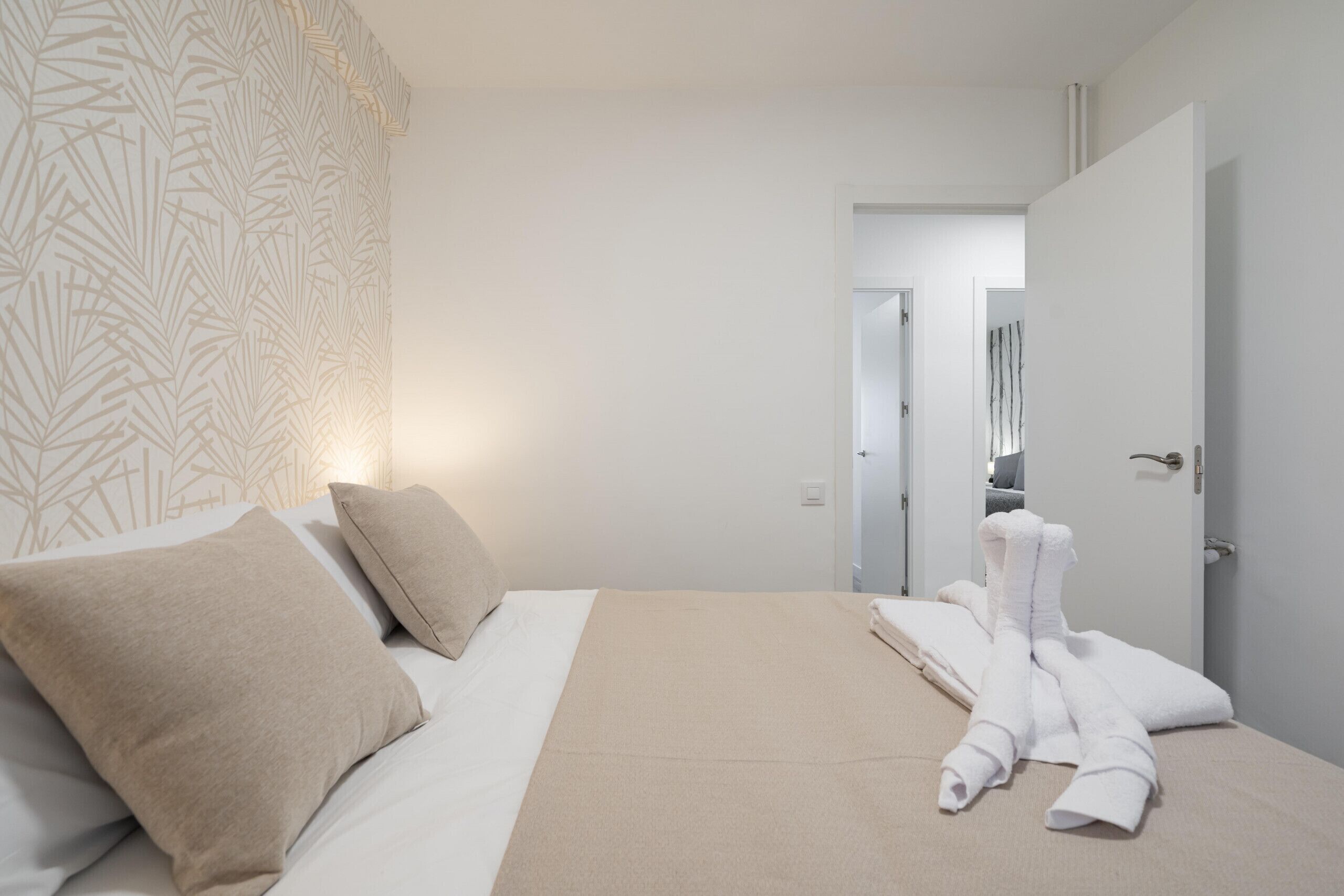 Una habitación de hotel con cama, almohadas, una manta y toallas.
