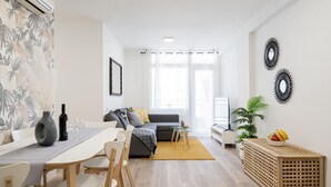 A modern living room with a sofa, dining table, chairs, and a coffee table.