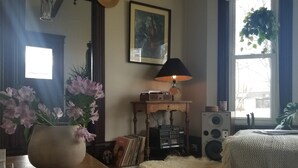 Een gezellige kamer met een houten tafel, een grote bloemenvaas, een vintage radio en een zacht tapijt.