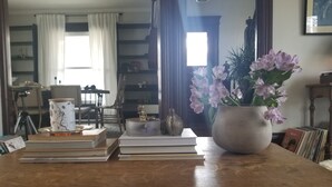 Een houten tafel met boeken, een bloevas en een lamp.