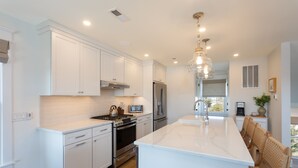 A modern kitchen with white cabinetry, stainless steel appliances, and a large island. - Oceanside home - 2 min walk to the beach! Ocean & bay views! (Ship Bottom)