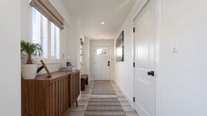 A hallway with a wooden bench, a potted plant, and a door at the end. - Oceanside home - 2 min walk to the beach! Ocean & bay views! (Ship Bottom)