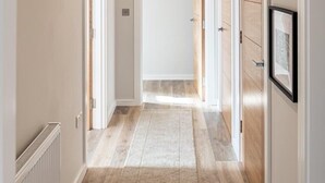 Un corridoio con pavimento in legno, un tappeto e quadri appesi al muro.