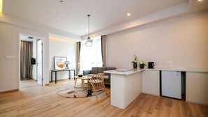 A modern kitchen with a central island, wooden flooring, and a dining area with a table and chairs. - Zhongjian Suisseplace Apart S Hotel (Shanghai)