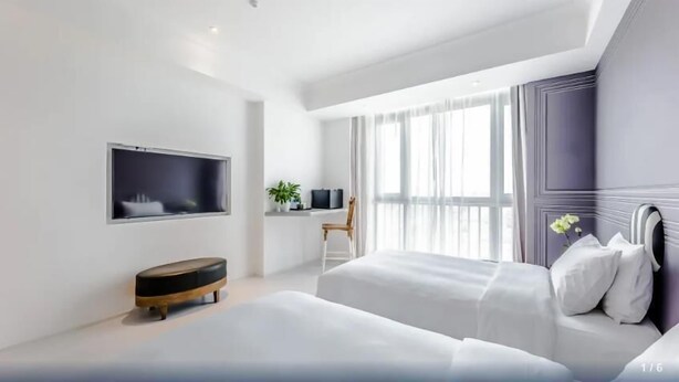 A modern hotel room with a large bed, a desk with a chair, a TV mounted on the wall, and a large window with sheer curtains. - Zhongjian Suisseplace Apart S Hotel (Shanghai)