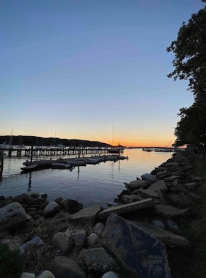 A calm waterfront scene with a pier extending into the water, surrounded by rocks and trees.