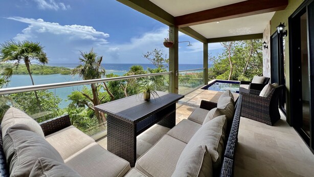 Un balcon avec coin salon extérieur, un jacuzzi et une vue sur l’océan.
