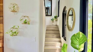 Un escalier avec des finitions en bois, un luminaire fixé au mur et un grand miroir.