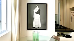 Een moderne keuken met een glazen tafel en een kunstwerk in een lijst aan de muur.