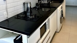 Een moderne keuken met witte kasten, een zwart aanrecht, een koffieapparaat, een wasmachine en een inbouwoven.