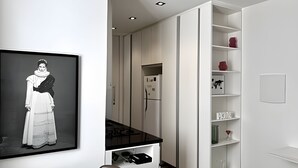 Een moderne keuken met witte kastjes, een zwart aanrecht en een koelkast.