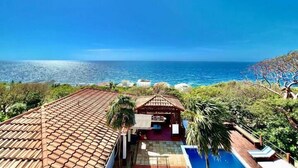 Una proprietà costiera con tetto in tegole, piscina e vista sull'oceano.
