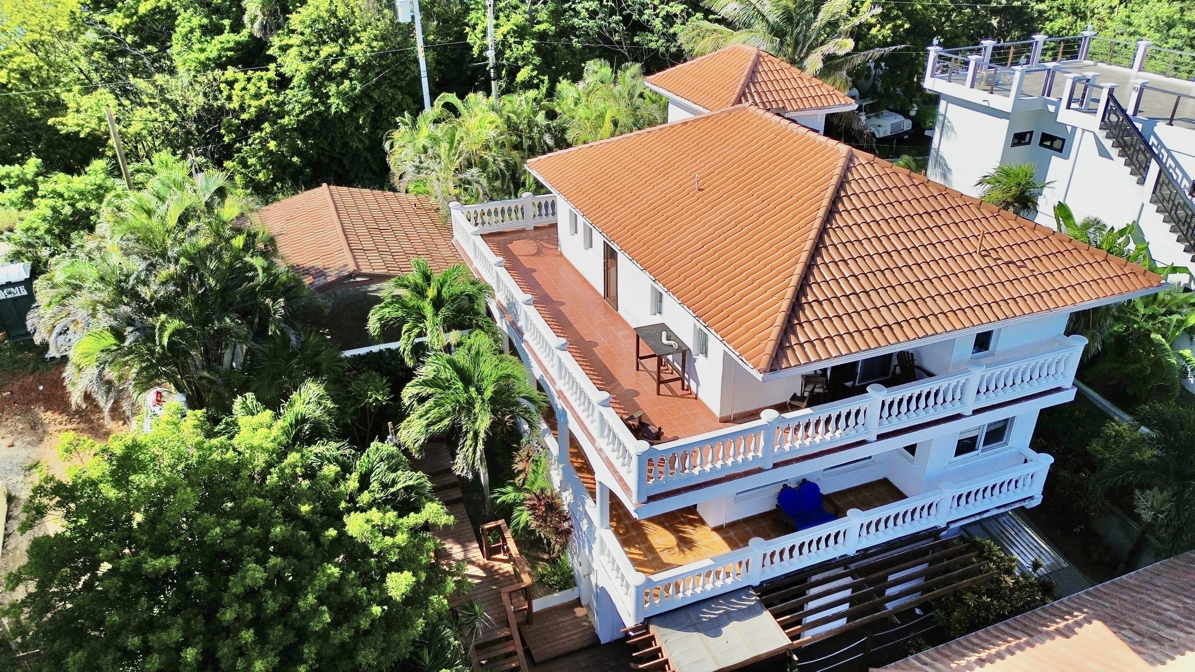 A multi-story building with a tiled roof, surrounded by lush greenery.