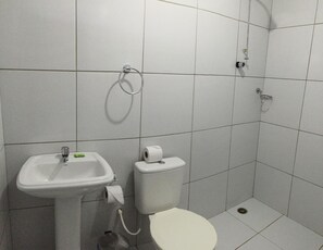 Un baño pequeño con azulejos, un lavamanos, un inodoro y una ducha.