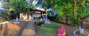 A house with a covered porch, a hammock, and a pathway leading to the entrance.