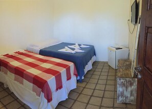 A small room with two beds, a television, a small refrigerator, and a wooden door.
