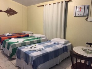 Ett hotellrum med två separata sängar, ett runt bord, en väggmonterad värmare och en gardin.