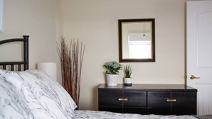 A bedroom with a bed, a dresser, a mirror, and a door. - The Cobourg Creek Cottage (Cobourg)
