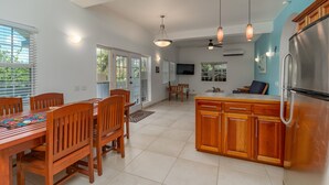 A spacious kitchen with wooden cabinets, a stainless steel refrigerator, and a dining area with a wooden table and chairs.