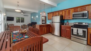 A spacious kitchen with wooden cabinets, stainless steel appliances, and a dining area with a colorful rug.