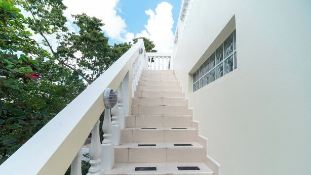 A staircase with white balustrades and beige steps leading to a balcony.