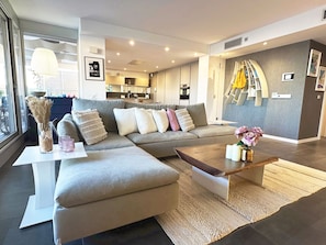 A modern living room with a sofa, coffee table, and a view of the kitchen.