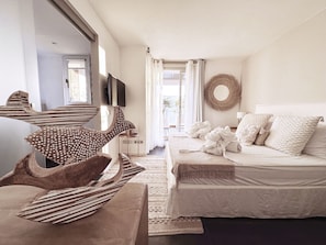 A bedroom with a bed, a television, a wall-mounted mirror, and a decorative wall hanging.