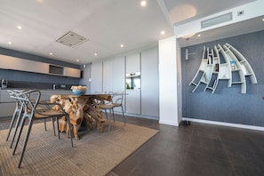 A modern kitchen with a dining area, built-in appliances, and a unique wall-mounted bookshelf.