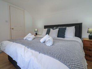 A hotel room with a bed, a nightstand, a lamp, and a door. - 4 Green Farm Cottage (Chester)