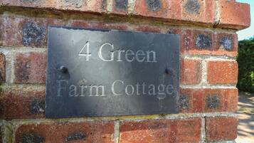 Una señal en una pared de ladrillo que dice '4 Green Farm Cottage'.