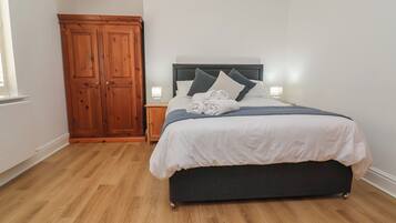 A bedroom with a bed, bedside lamps, a wardrobe, and a window.