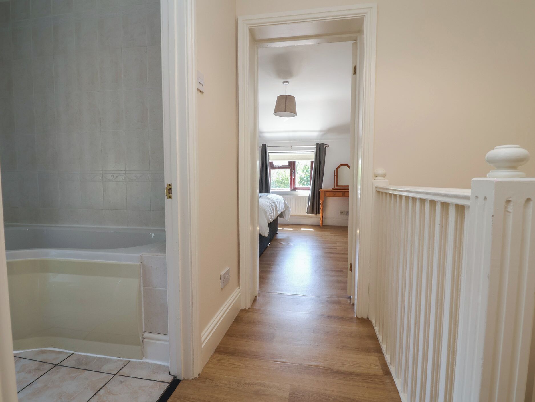 A hallway with a bathtub, a radiator, and a bed in the background.