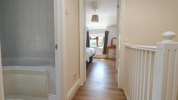 A hallway with a bathtub, a radiator, and a bed in the background.