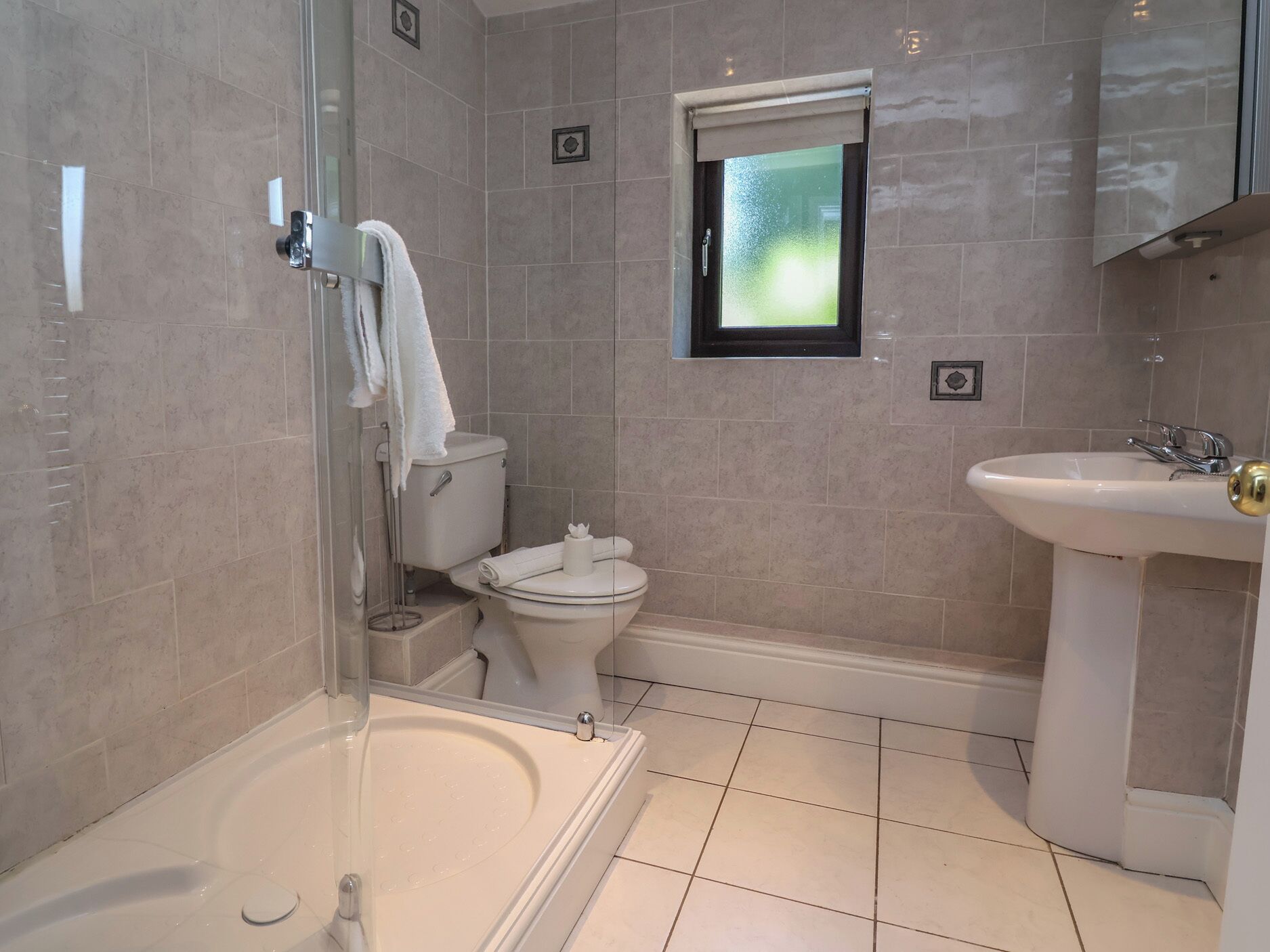 Un baño moderno con ducha de vidrio, inodoro y lavamanos.