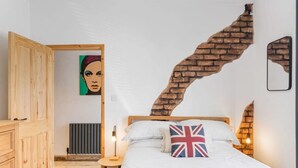 Et soveværelse med et træskab, en seng med pude med Union Jack-motiv, en murstensbue og en radiator.
