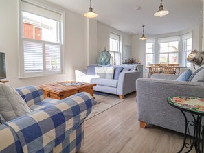 A living room with a sofa, armchair, coffee table, and a dining area with a table and chairs.