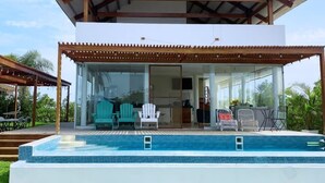 Una casa moderna con piscina, terraza techada y zona de estar exterior.
