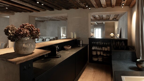 Una cocina moderna con encimera de madera, estufa integrada y un armario negro con vajilla.