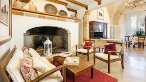 A cozy living room with a fireplace, wooden furniture, and stone walls. - Tenuta Cavalieri - Camera Quadrupla (Leverano)