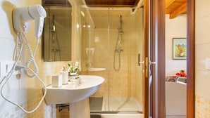 A bathroom with a glass-enclosed shower, a hairdryer, a sink, and a mirror. - Tenuta Cavalieri - Camera Quadrupla (Leverano)