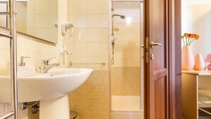 A bathroom with a sink, mirror, and shower.