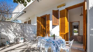Eine Terrassenfläche mit Esstisch, Holzläden und einer Klimaanlage.