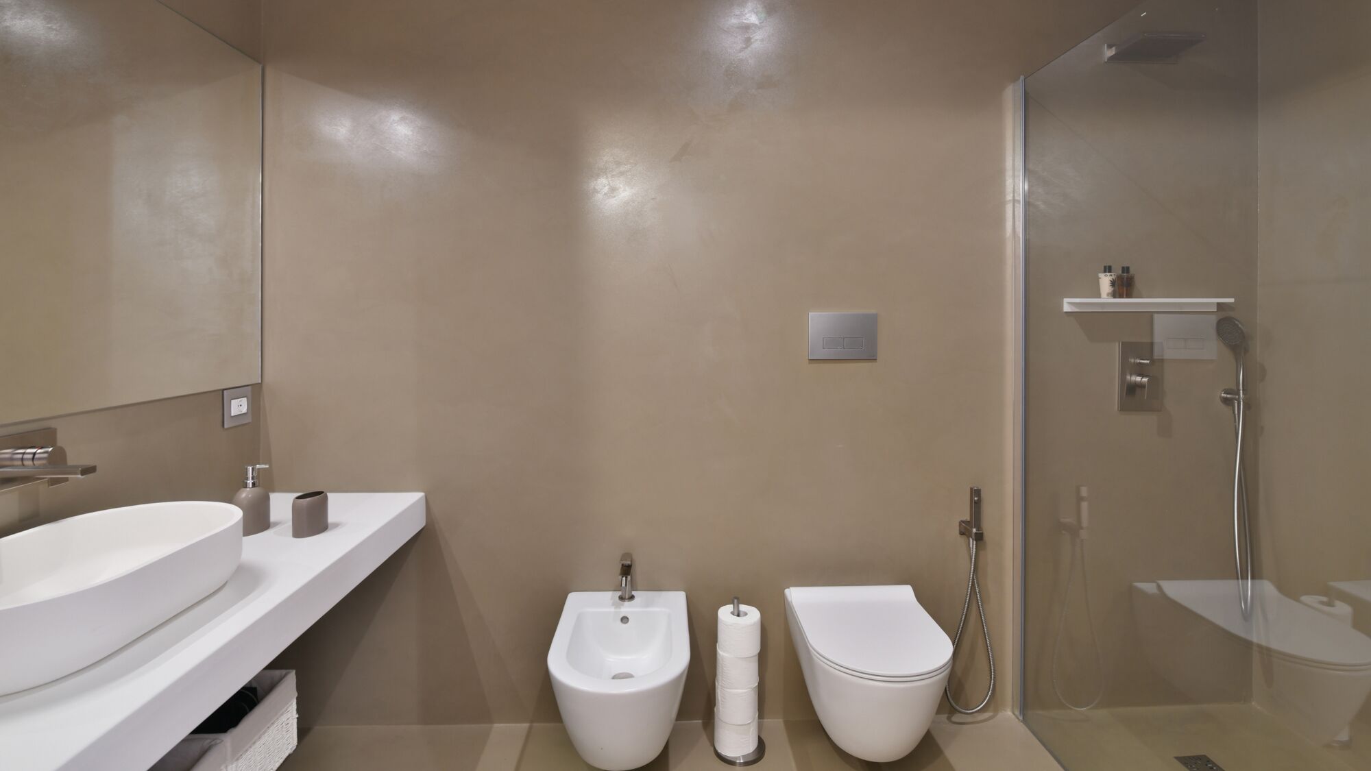 A modern bathroom with a large sink, bidet, toilet, and shower.