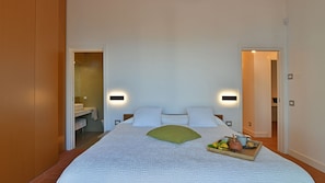 A bedroom with a large bed, two bedside tables, a nightstand, a bedside lamp, and a tray with fruits and a teapot on the bed. - Villa Armonia 8, Emma Villas (Pollina)