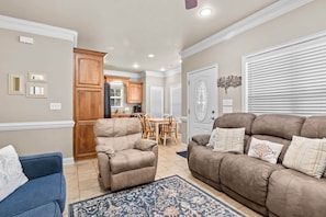A living room with a brown sofa, a blue armchair, and a patterned rug.