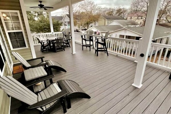 A covered porch with outdoor furniture and a white railing. - Upscale Beach House-Linens|Golf Cart|Quiet Area (Myrtle Beach)